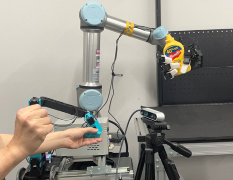 Teleoperation setup with a GELLO leader arm, one RGB camera and the UR5e-mounted hand
